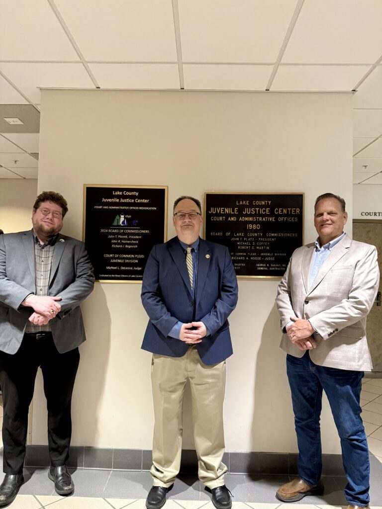President of the Board of Commissioners Richard J. Regovich and Commissioner John T. Plecnik and Judge DeLeone revealing plaque