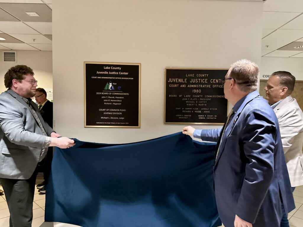 President of the Board of Commissioners Richard J. Regovich and Commissioner John T. Plecnik and Judge DeLeone revealing plaque